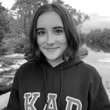 Profile photo for Amy Meek, Youth Action Lead at Common Seas. Amy wears a hooded jumper with 'KAP' (Kids Against Plastic) embroidered across the chest. She is smiling at the camera. Photo is in greyscale
