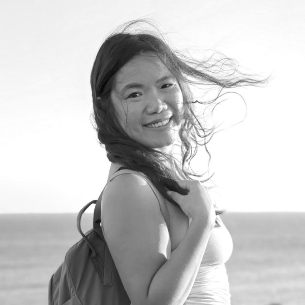 Profile photo of Celia Siura, Chief Operating Officer of Common Seas Indonesia. Celia wears a backpack and vest top, and smiles at the camera from side on. Photo is in gresycale.