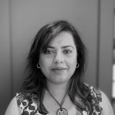 Profile photo of Faryal Gohar, Project Manager at Common Seas. Faryal wears a short-sleeved patterned blouse and a pendant necklace, and is smiling at the camera. Photo is in greyscale.