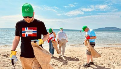 A beach clean-up in Greece, with a figure walking towards the camera holding a sack.