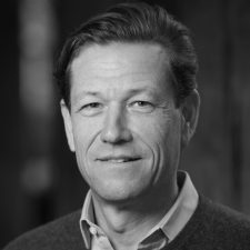 Profile photo for Simon Harrison, Director of Common Seas. Simon wears a dark jumper with a light shirt, and is smiling at the camera. Photo is in greyscale