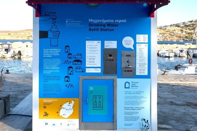 Photo of a water refill station on the Greek island of Paros. The refill station is a blue freestanding metal dispenser with space to refill a reusable bottle